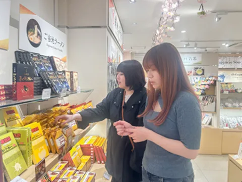 小町通りのお店で食べ歩きグルメを選ぶ様子